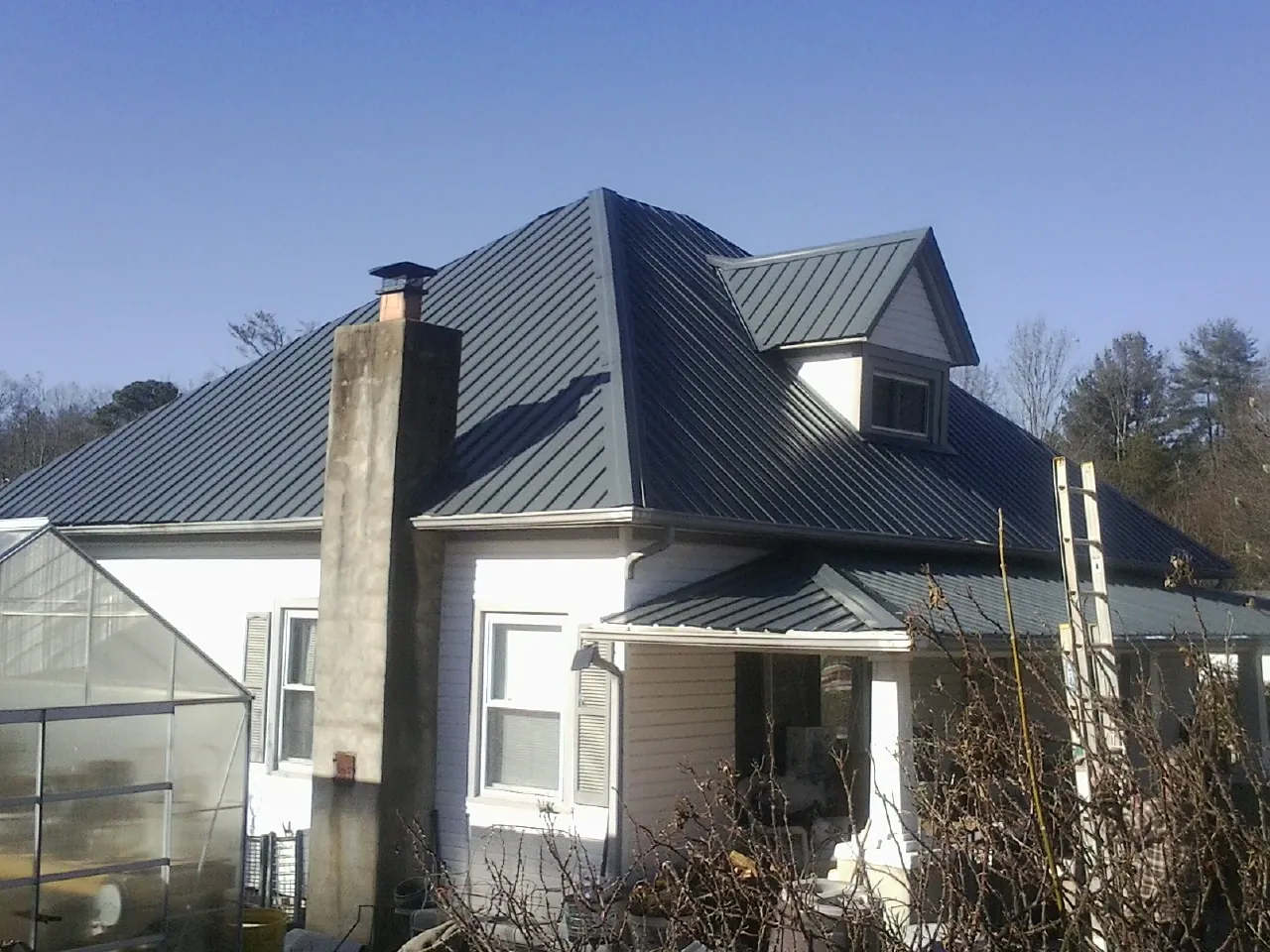 Dark blue standing seam metal roof on a white farmhouse with dormer — Slate & Tile Roof Repair by Roofing Brothers in Rillito
