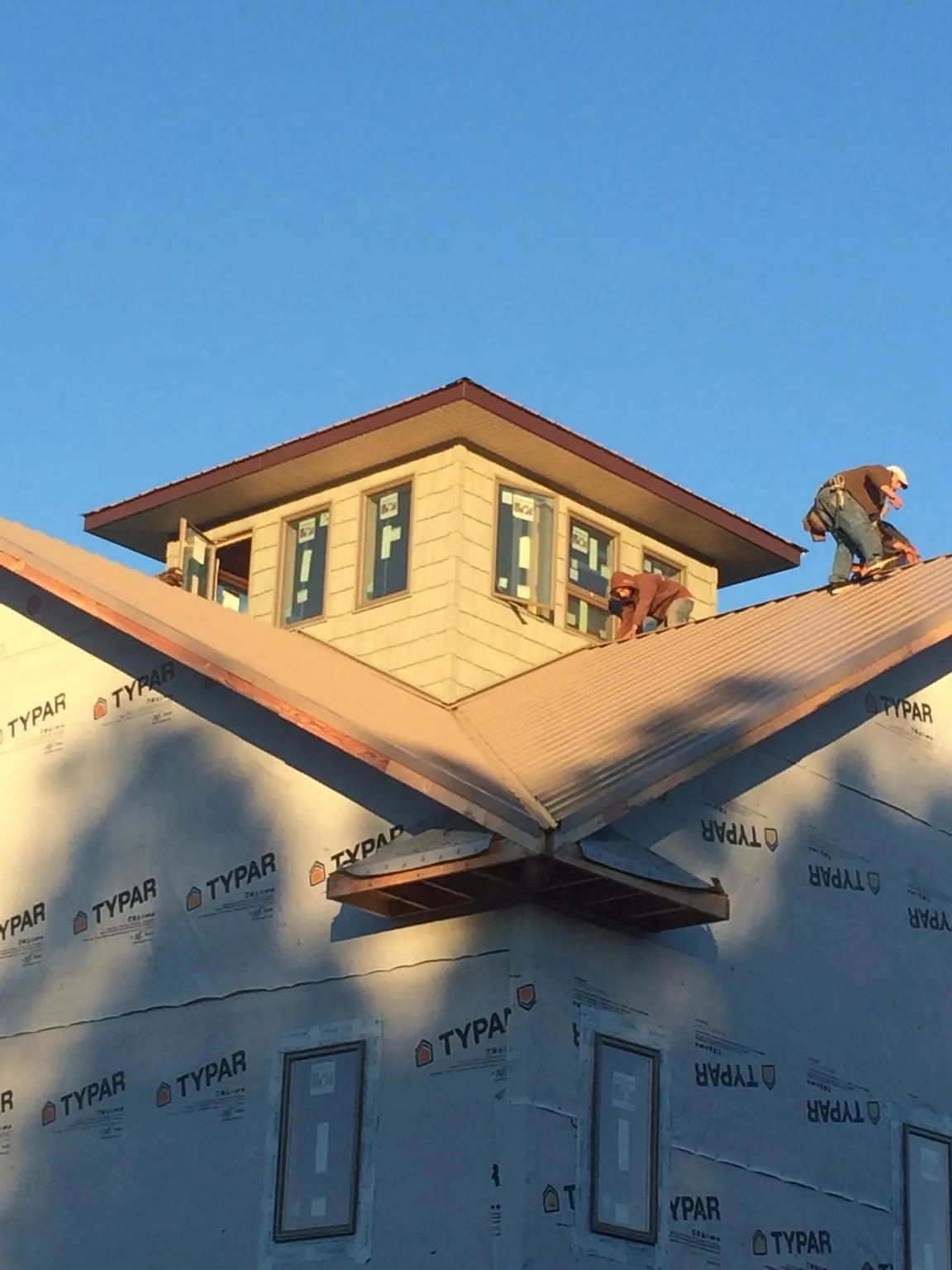 Roofers working around a rooftop cupola on a new metal roof at sunset — Roof Waterproofing in Rillito by Roofing Brothers
